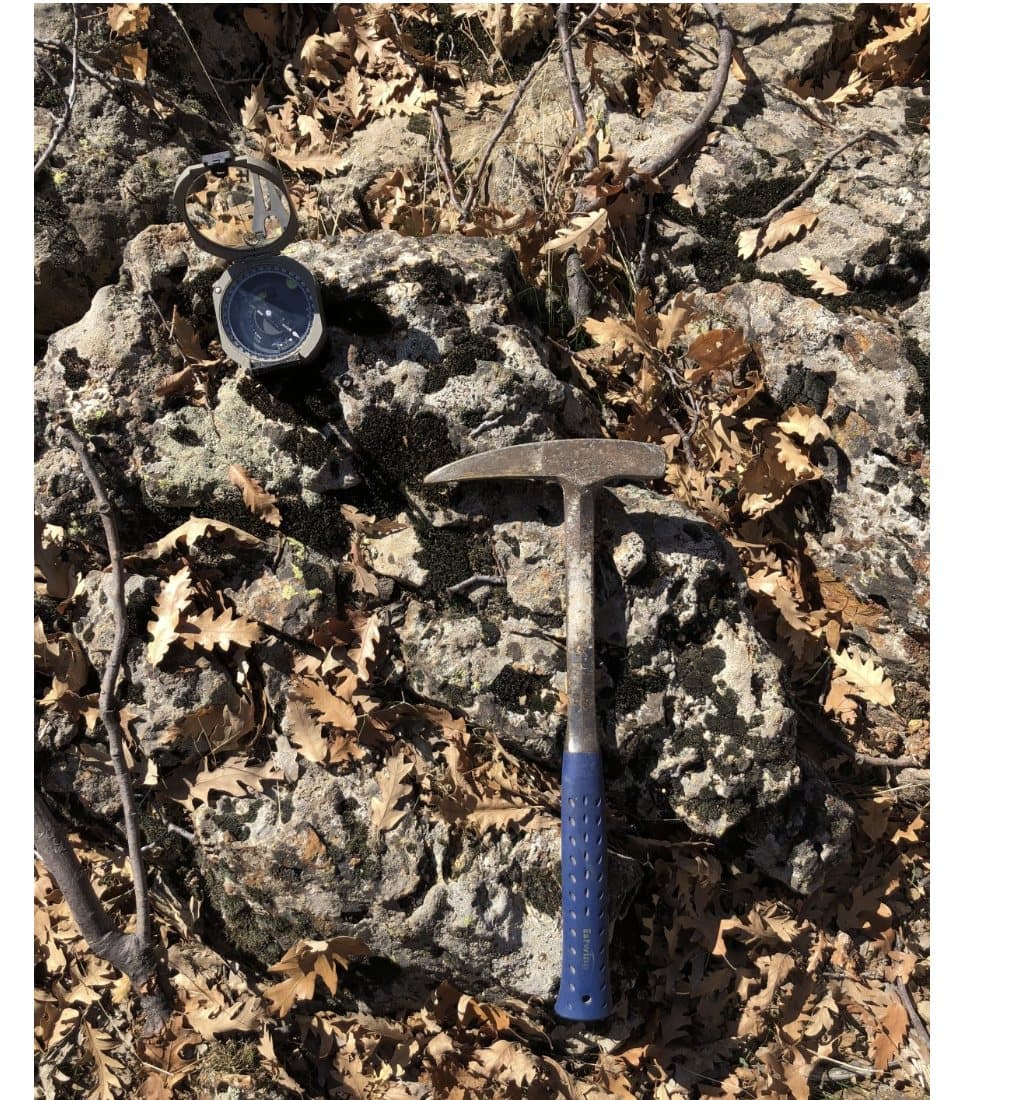 Geologist's hammer and compass-clinometer resting on rock outcrop